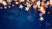 Star shaped Christmas string lights on blue night background with golden bokeh lights