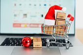 Christmas Online Shopping concept. Boxes with shopping cart on a laptop computer. Sale and discount during Christmas and New Year holiday, ecommerce, shipping delivery, logistics and Cyber Monday