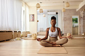 African American woman meditating in Lotus position at Yoga studio.