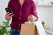 Man holding shopping bags and checking smartphone for black friday deals