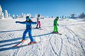 Teen girl and two young boys skiing on snowy slope