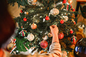 Close up to hands hanging knick knacks on Christmas tree.