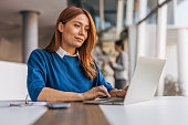 A successful businesswoman is using a laptop and working in the office