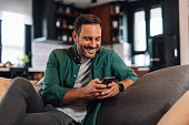 Man relaxing on the sofa using his smartphone