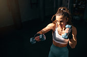 Female kickboxer shadowboxing with dumbbells