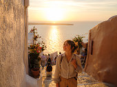 Woman walking on streets on Santorini island at sunset