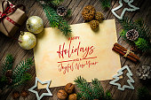 Happy Holidays greeting card or invitation for Christmas or December, text or message. Rustic wood table and old fashioned background. Flat lay and decor, gift box and fir tree border