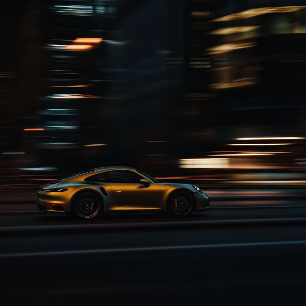 Long Exposure Photo of Golden Porsche Driving Fast Through Metropolis Free Image