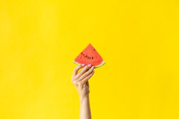 Slice of Watermelon in Woman Hand on Bright Yellow Background Free Photo